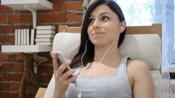 Νεαρή γυναίκα ακούει μουσική στο Smartphone, ακουστικά — Αρχείο Βίντεο