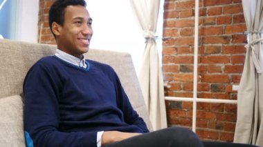 Loft arka plan ile oturan gülümseyen genç Afrika adam