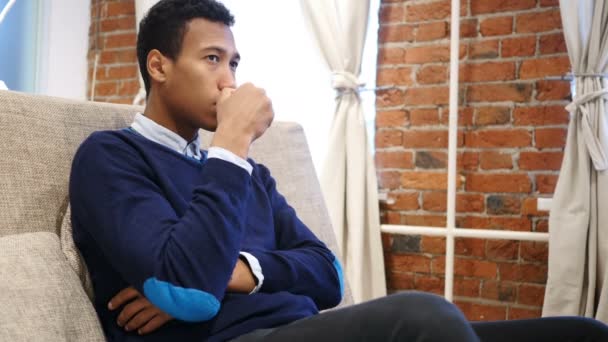 Joven africano bebiendo café de la taza sentado en el sofá — Vídeo de stock