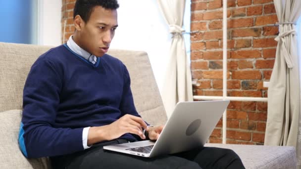 Giovane uomo africano che celebra il successo mentre lavora sul computer portatile — Video Stock