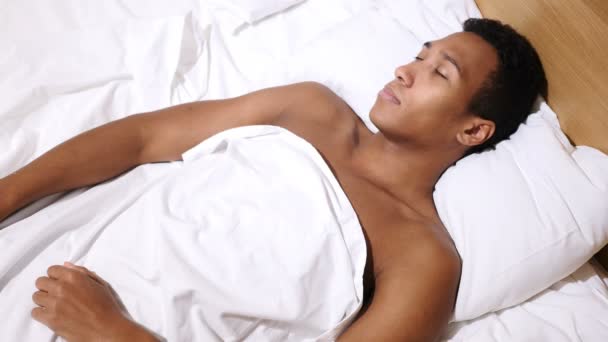 Blick von oben auf einen entspannten jungen Afrikaner, der nachts im Bett schläft — Stockvideo
