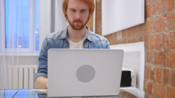 Рудий бородатий чоловік працює на ноутбуці в — стокове відео