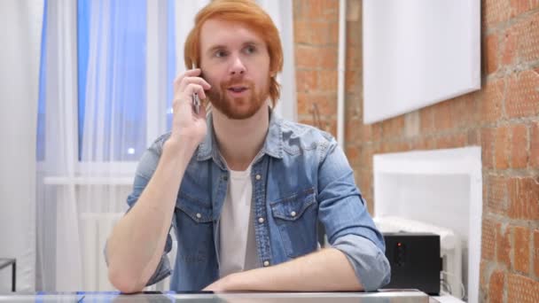 Человек с рыжей бородой разговаривает по телефону, посещает телефонный звонок — стоковое видео