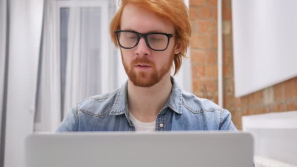 Homem de barba ruiva na cama trabalhando no laptop e reagindo ao sucesso — Vídeo de Stock