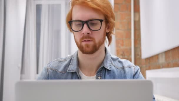 Cansado pelirrojo barba hombre tratando de relajarse, mientras que el trabajo en el ordenador portátil — Vídeos de Stock