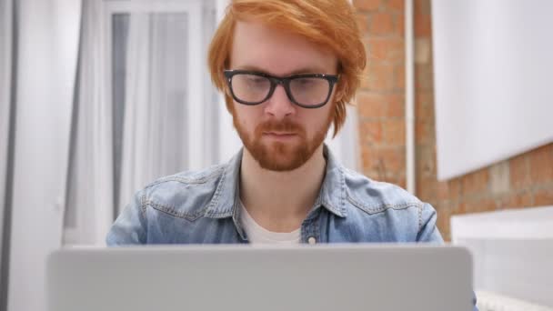 Potrząsanie głową na nie, Ruda broda człowiek pracuje na laptopie — Wideo stockowe