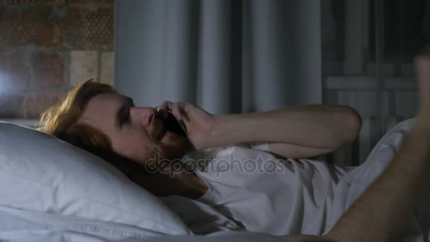 Ruda broda mężczyzna w łóżku uczestniczy rozmowy i rozmowy na telefon — Wideo stockowe