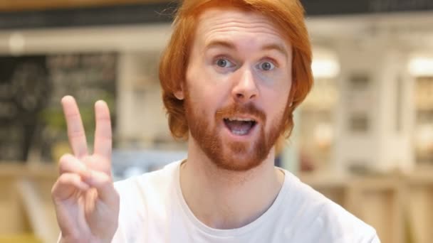 Retrato de homem de barba ruiva Gesturing Victory Entre Café — Vídeo de Stock