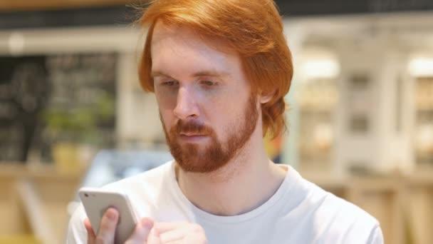 Redhead skägg Man använder Smartphone för Online surfa — Stockvideo