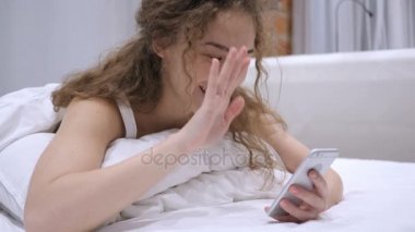Yatakta güzel kadın tarafından smartphone cep telefonu ile Video sohbet