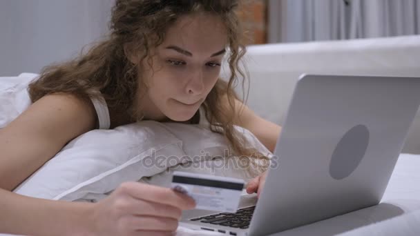 Feminino na cama usando cartão bancário para pagamento on-line no laptop — Vídeo de Stock