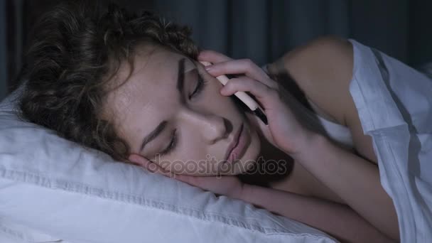 夜ベッドで携帯電話で話している女性の顔のクローズ アップ — ストック動画