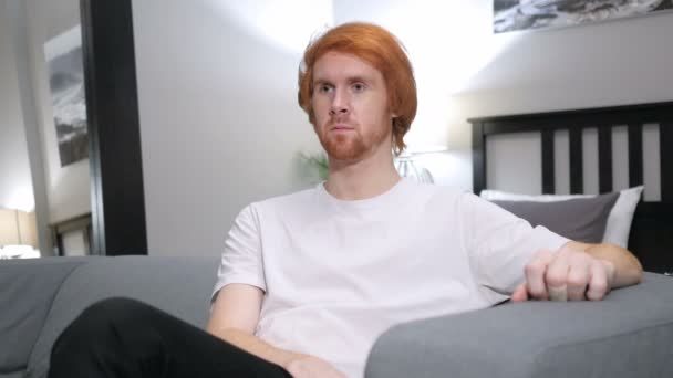 红头发的男人坐在沙发上的卧室 — 图库视频影像