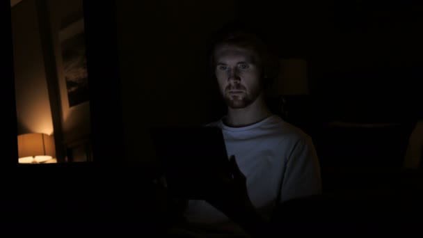 За допомогою планшетного ПК пізньої ночі в темній кімнаті, руда людина — стокове відео