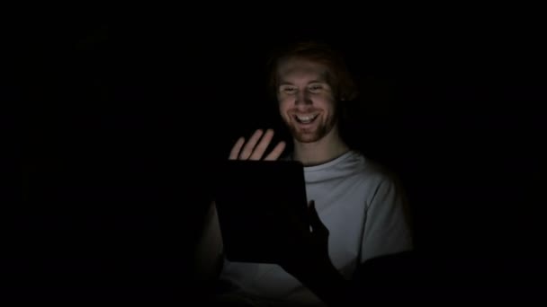 赤毛の男がタブレットに夜遅くまでビデオ チャット — ストック動画