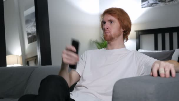 Tv-nézés, a változó csatornát a távoli vörös hajú ember — Stock videók