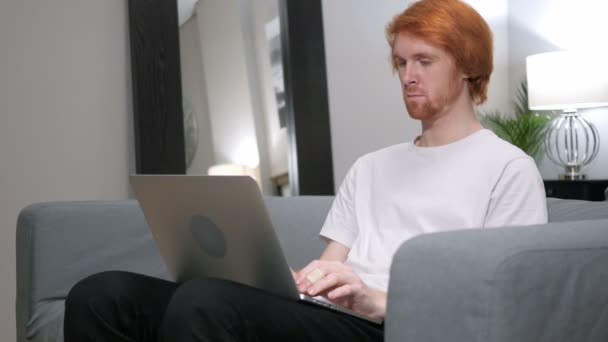 Casual pelirroja hombre trabajando con el ordenador portátil en su vuelta — Vídeo de stock