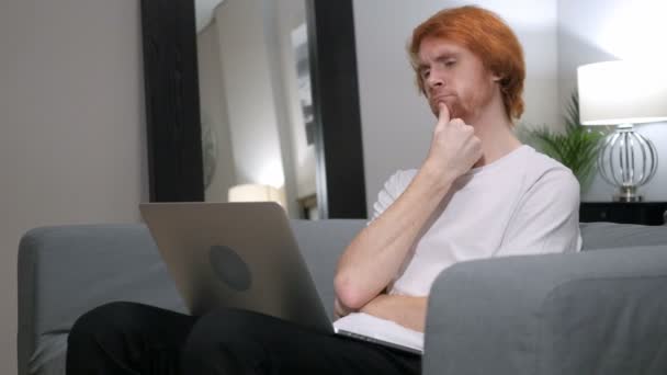 Zamyšlený Redhead člověka pracovat na notebooku v ložnici — Stock video