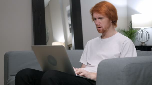 Zlobí čím dál hlasitější Redhead člověka pracovat na notebooku v ložnici — Stock video