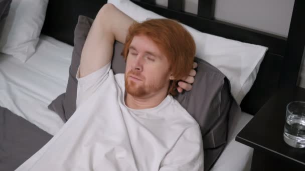 Jeune homme rousse fatigué dormant au lit — Video