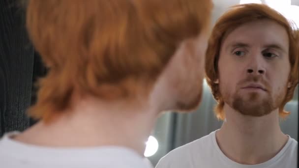 Рыжеволосый бородач проверяет свои зубы в зеркале — стоковое видео