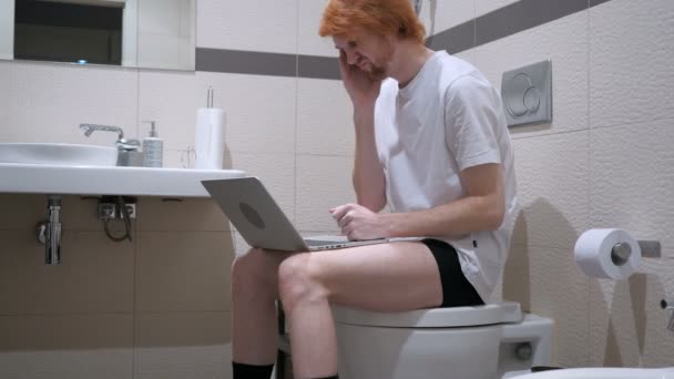 Ból głowy, zmęczony człowiek korzysta z laptopa w łazience, komody — Wideo stockowe