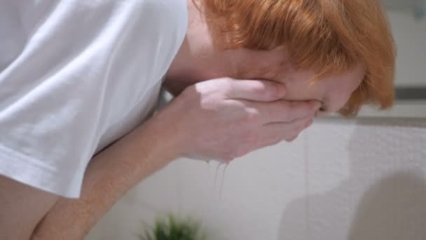 Rothaarige mann waschen gesicht im waschbecken, waschraum — Stockvideo