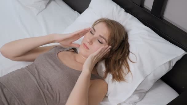 Nő feküdt az ágyban, fejfájás, fájdalom a fej — Stock videók