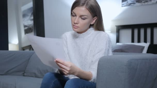 Молода жінка читання лист сидячи на дивані — стокове відео
