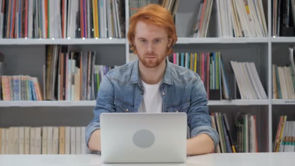 Jonge Man aan het werk op Laptop in bibliotheek — Stockvideo