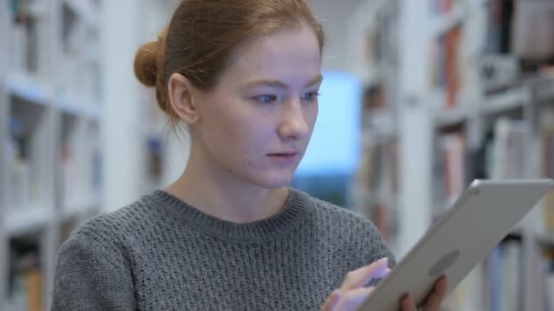 Κοκκινομάλλης γυναίκα βιαστικά Διαδίκτυο στο Tablet στην εργασία — Αρχείο Βίντεο