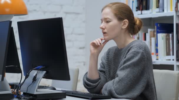 Pensando rossa donna che lavora sul computer portatile, seduto in ufficio — Video Stock