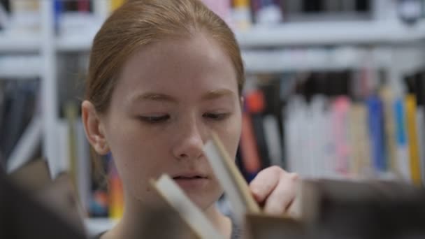 Närbild av kvinna söka efter boken i biblioteket — Stockvideo