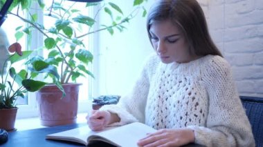 Genç kadın ofiste otururken kitap okumak