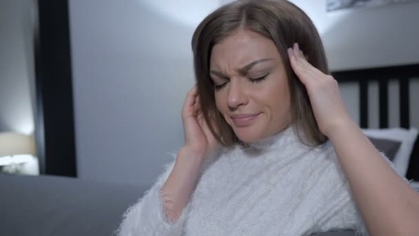 Mujer cansada sentada con dolor de cabeza en el dormitorio, dolor — Vídeos de Stock