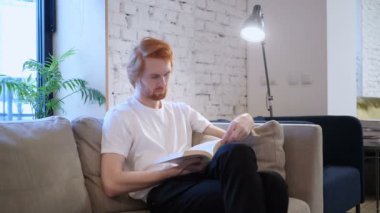 Yaratıcı Casual adam kanepede oturup kitap okumak