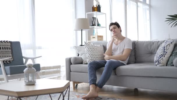 Pensive Young Man Thinking while Sitting on Sofa at Home — Stock Video