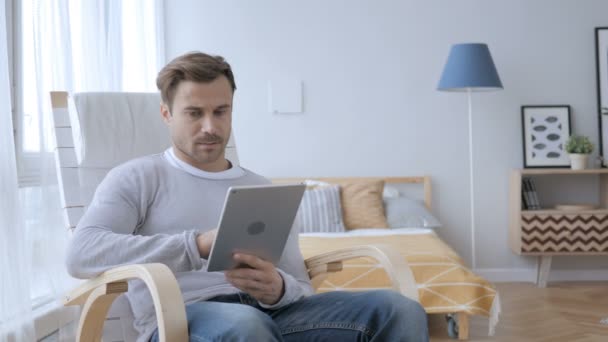 Чоловік сидить на стільці Інтернет на планшеті — стокове відео