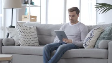 Yetişkin adam oturan kanepe ve Tablet kullanma
