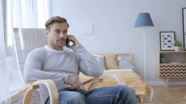 Hombre adulto hablando por teléfono mientras se relaja en la silla — Vídeos de Stock