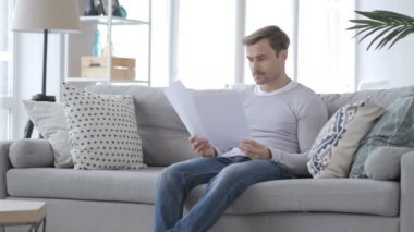 Belgeleri kanepede otururken yetişkin adam okuma Penisve