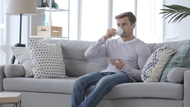 Hombre adulto bebiendo café y relajándose en el sofá — Vídeos de Stock