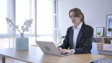 Ofiste dizüstü bilgisayarda çalışan yorgun genç bir kadın.
