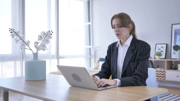 Втомлена молода жінка працює на ноутбуці в офісі — стокове відео