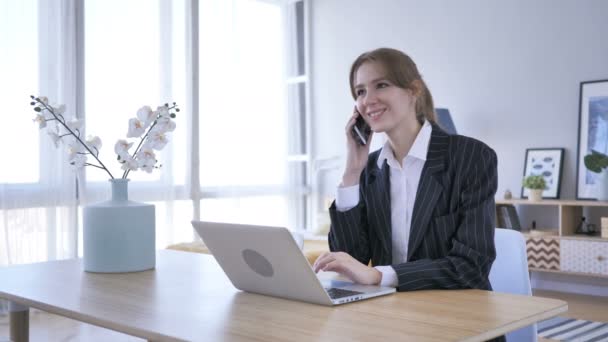 Ung kvinna deltar i samtal på jobbet, pratar telefon — Stockvideo