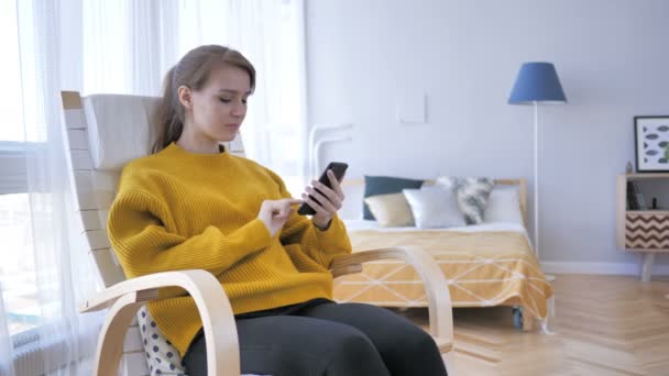 Mujer joven ocupada usando Smartphone mientras se relaja en la silla — Vídeos de Stock