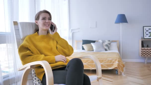 Genç kadın konuşurken telefonu dinlenirken sandalye üzerinde iken — Stok video