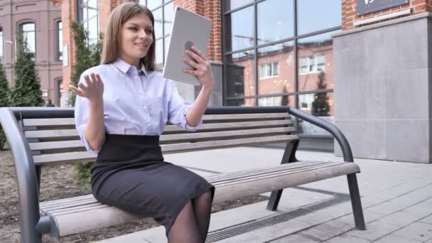 Онлайн видео чат на планшете от женщины, сидящей вне офиса — стоковое видео