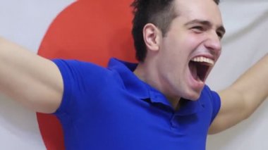 Japon genç adam ağır çekimde Japon bayrağı tutarken kutluyor