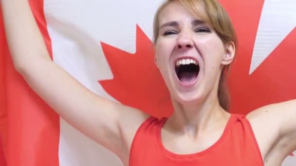 Mujer joven canadiense celebrando mientras sostiene la bandera de Canadá en cámara lenta — Vídeo de stock